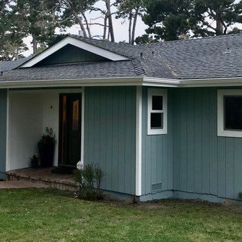 Green and white single-story residential shed with pitched roof and front entrance door