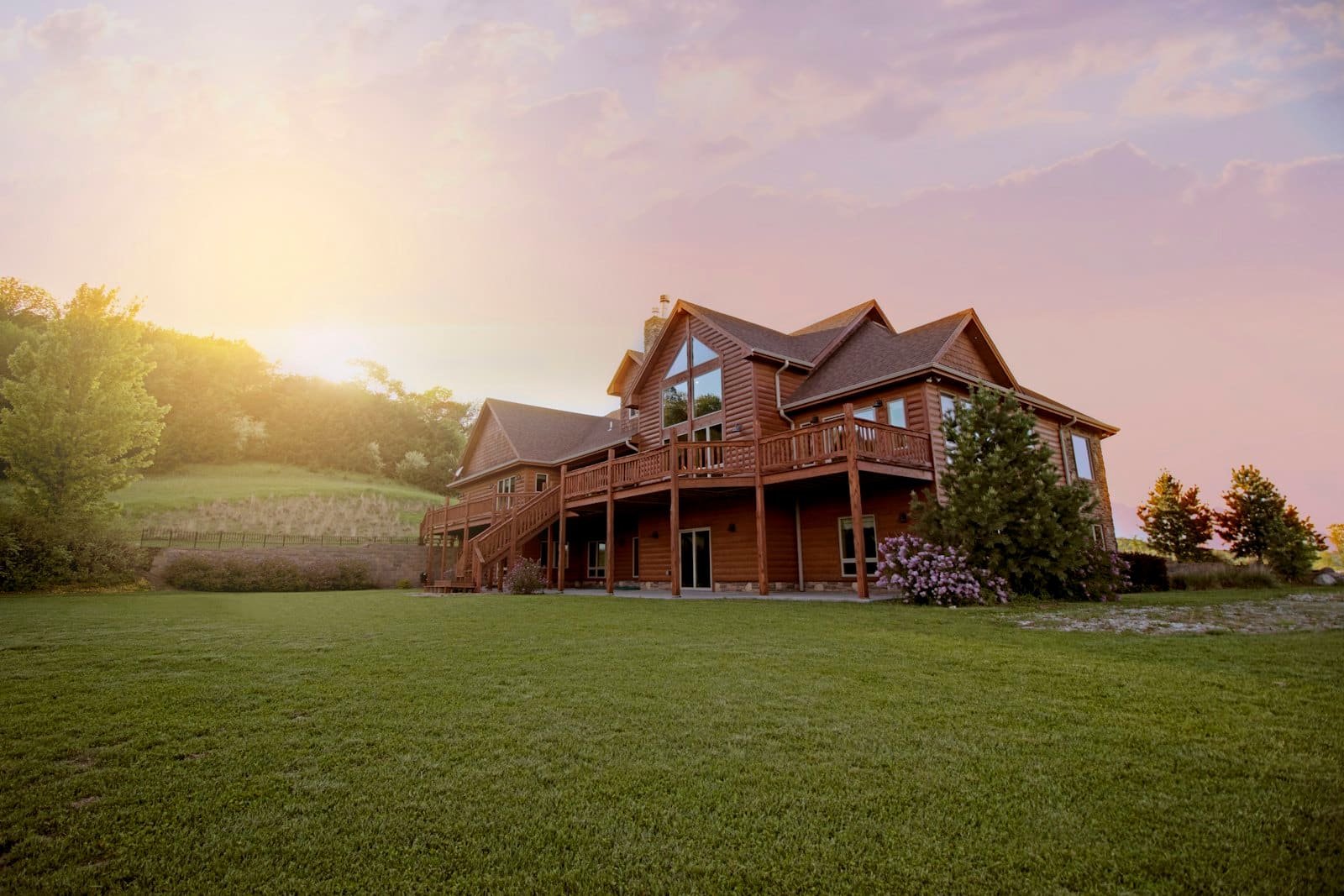 Luxury log home at sunset with manicured lawn and mountain views